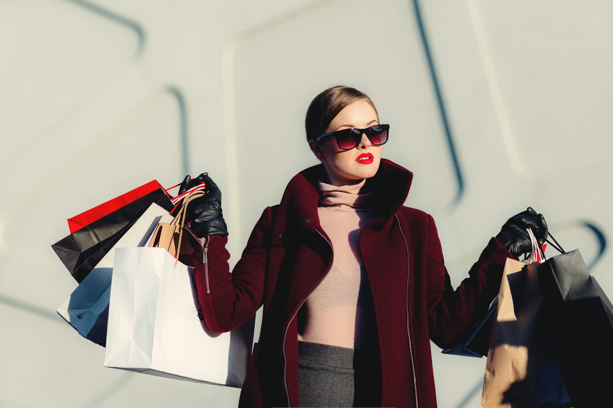 A woman in a maroon coat carrying shopping bags