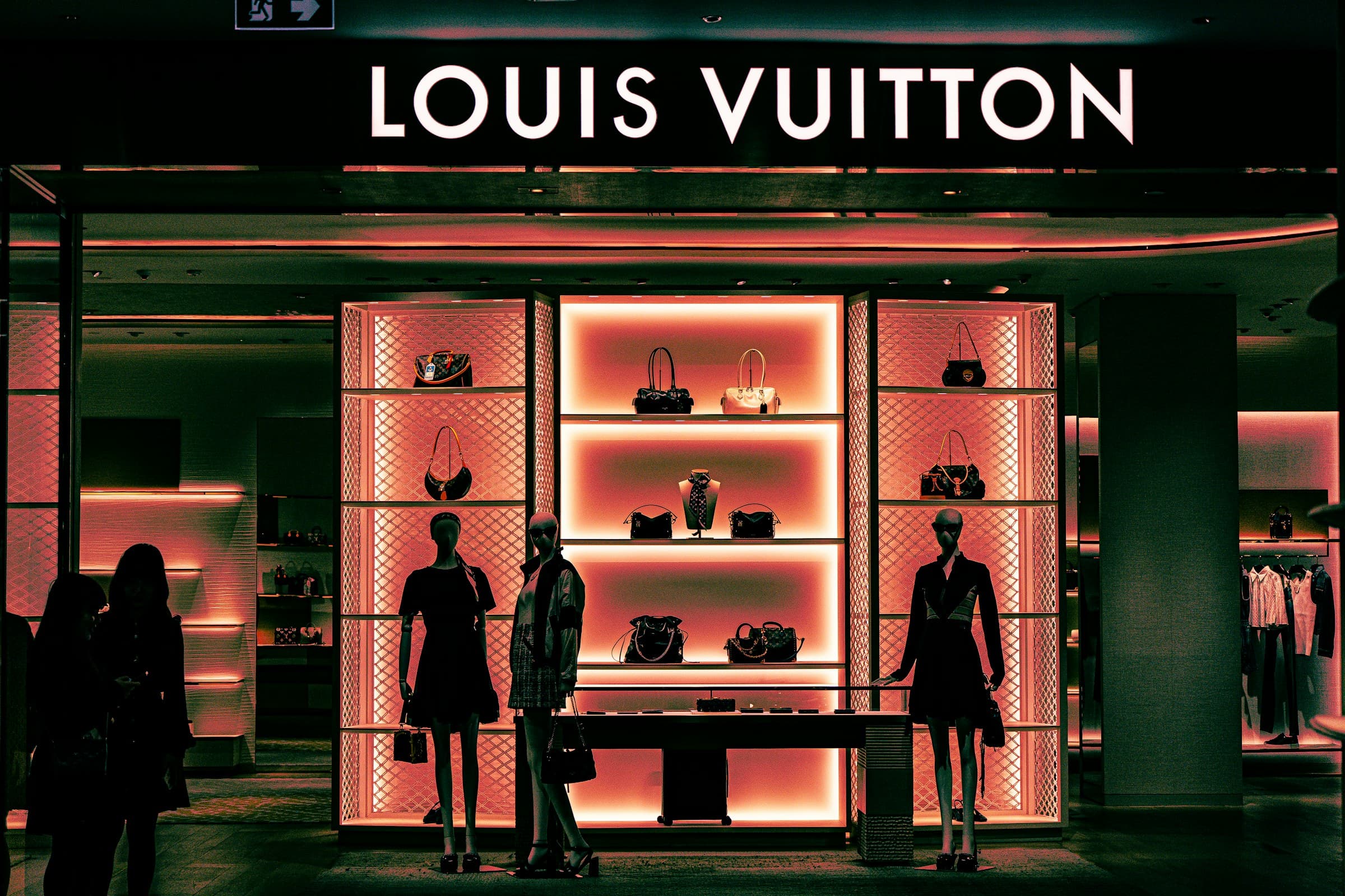 The warmly lit interior of a luxury boutique, handbags glowing on display