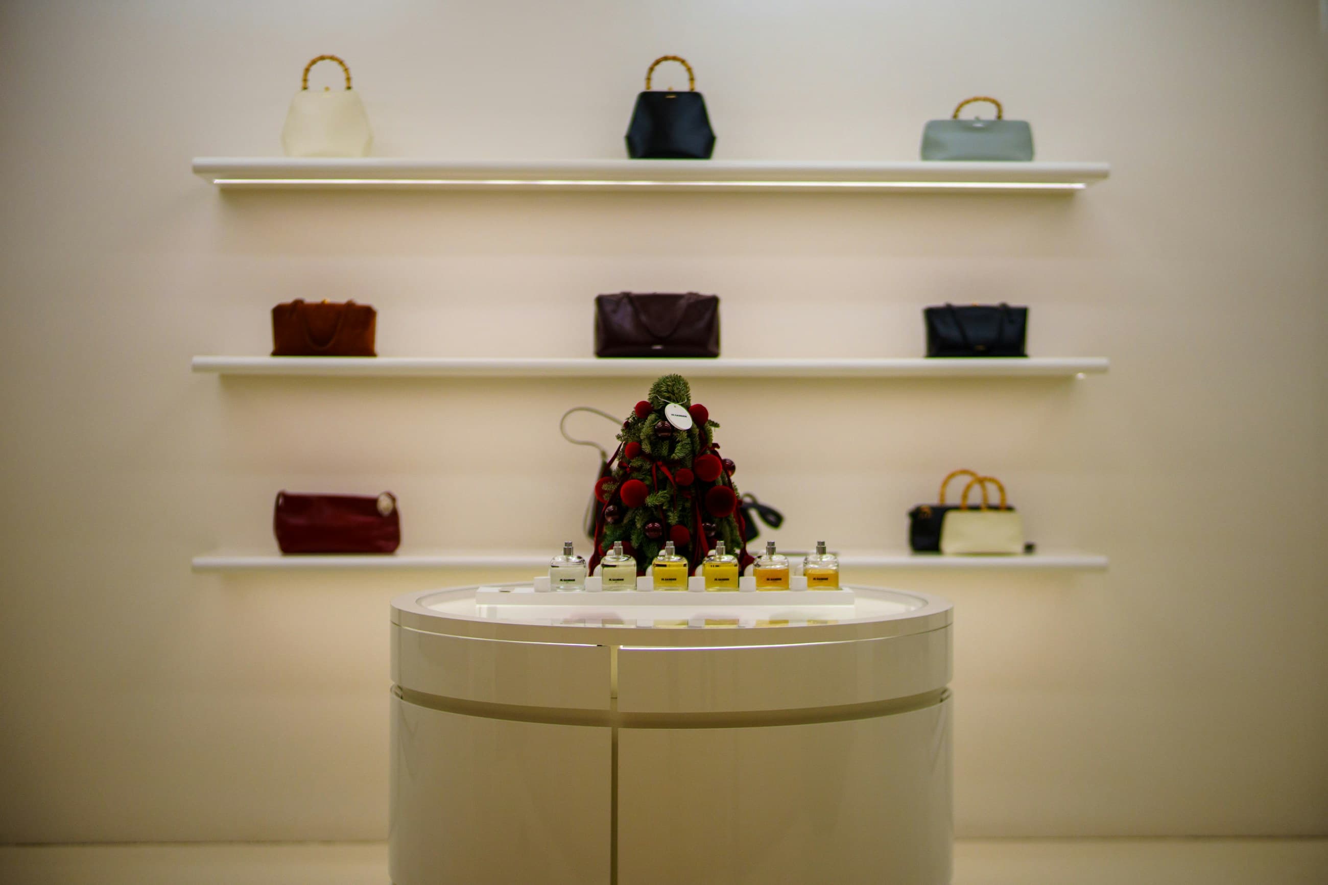 Designer handbags arranged on illuminated shelves in a cream luxury boutique
