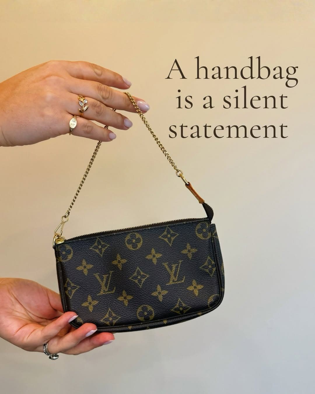 A handbag is a silent statement — a Louis Vuitton pochette held up by hand